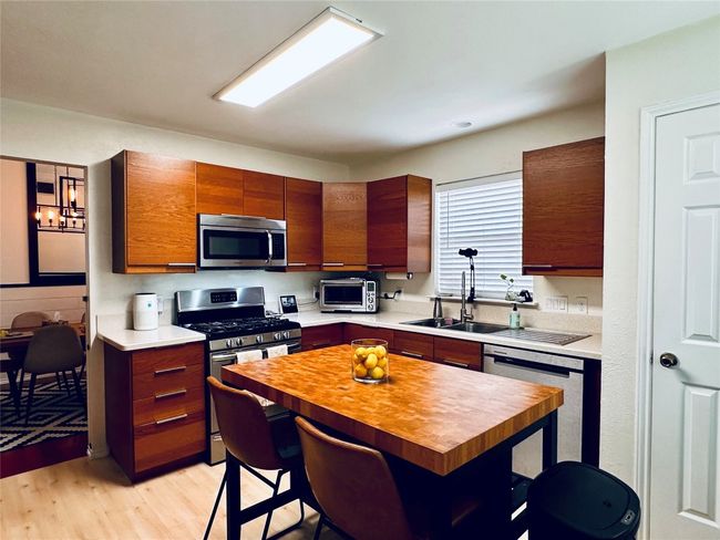 Kitchen featuring a breakfast bar area, light wood finished floors, a sink, and appliances with stainless steel finishes | Image 8