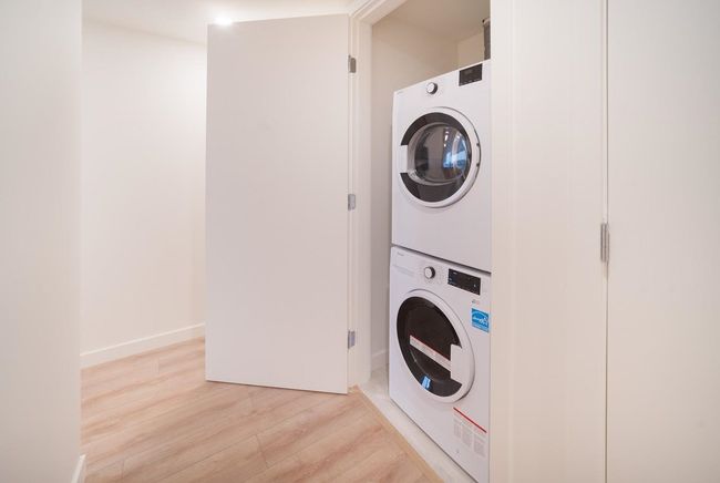 Laundry room with stacked washing machine and dryer and light wood-type flooring | Image 15