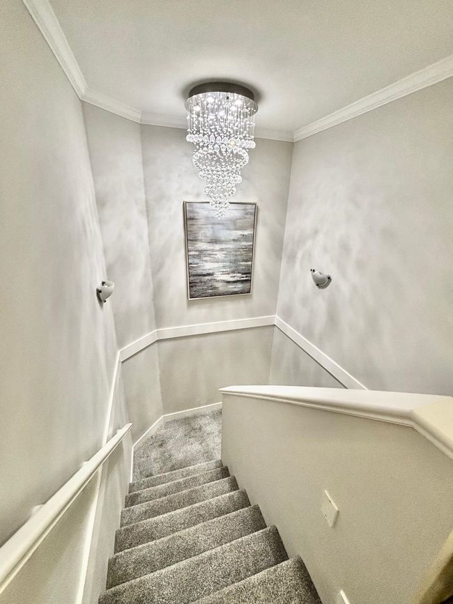 Stairway with carpet, a chandelier, and crown molding | Image 13