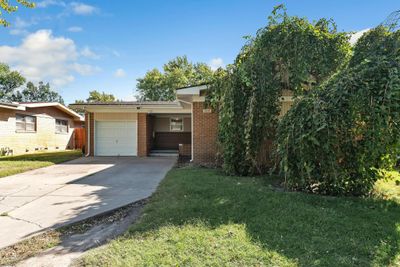 View of front facade with a front lawn, a carport, and a garage | Image 1