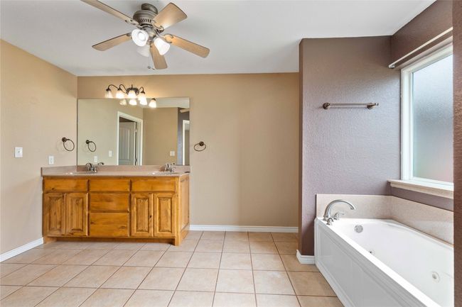 Full bath featuring healthy amount of natural light, a jetted tub, double vanity, and ceiling fan | Image 11