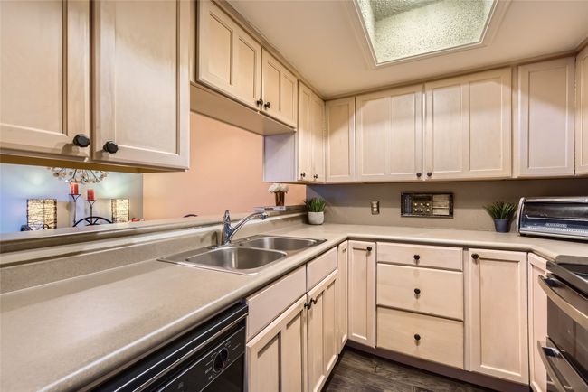 Kitchen featuring a sink, dishwasher, light countertops, dark wood-style flooring, and stove | Image 7