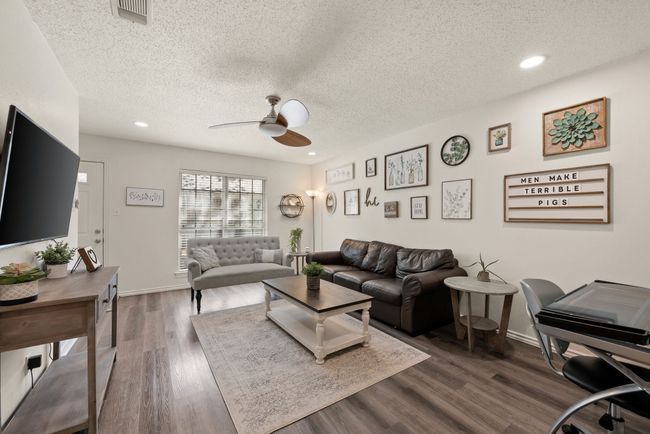 Living room with a textured ceiling, ceiling fan, dark wood finished floors, baseboards, and visible vents | Image 4