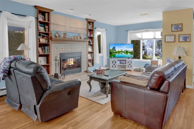 Living room with a tiled fireplace, light hardwood / wood-style floors, and baseboard heating | Image 12