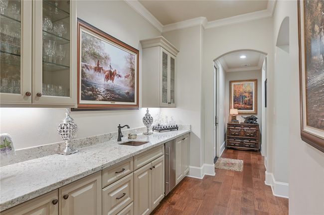 Bar area featuring arched walkways, a sink, ornamental molding, dark wood-type flooring, and baseboards | Image 9