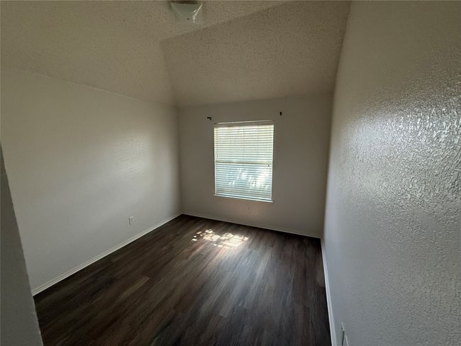 Unfurnished room featuring dark wood-style floors, baseboards, a textured ceiling, lofted ceiling, and a textured wall | Image 24