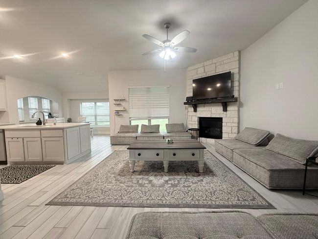 Living room featuring ceiling fan, light wood-style flooring, and a fireplace | Image 6