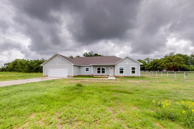 Single story home featuring roof with shingles, concrete driveway, an attached garage, and board and batten siding | Image 10