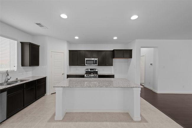 Kitchen featuring appliances with stainless steel finishes, a center island, light stone counters, recessed lighting, and decorative backsplash | Image 14