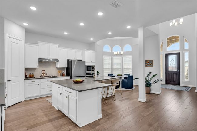 Kitchen with stainless steel appliances, a chandelier, a center island with sink, and white cabinets | Image 5