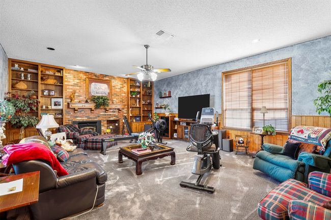 Living room with ceiling fan, a textured ceiling, a fireplace, and carpet flooring | Image 19