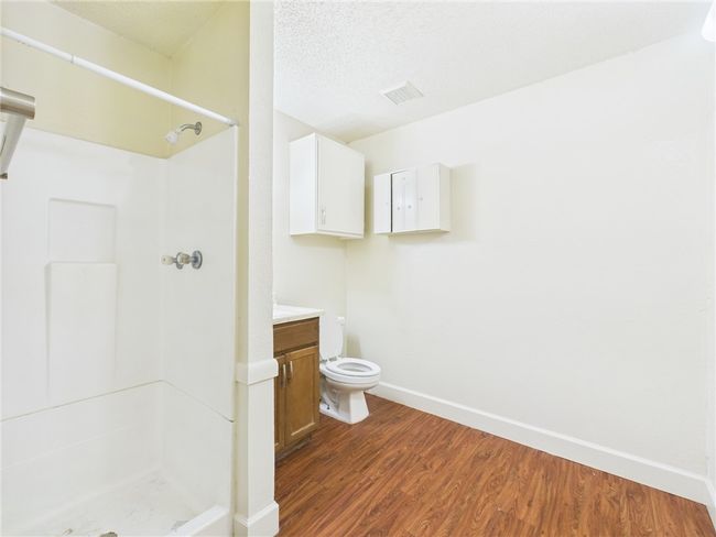 Bathroom featuring a shower, wood finished floors, vanity, and a textured ceiling | Image 10