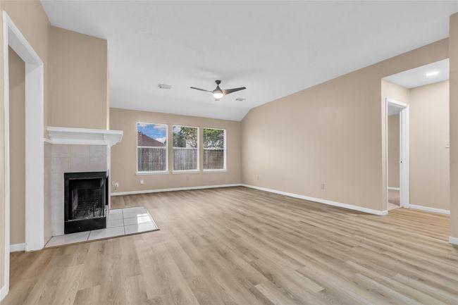 Bright and spacious living room features newly installed Vinyl flooring, a gas log fireplace and large windows. | Image 4