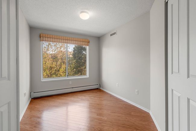 Bedroom two features engineered wood flooring, a spacious closet, and a window overlooking the side of the complex. It is also conveniently located just steps from the in unit laundry closet. | Image 12