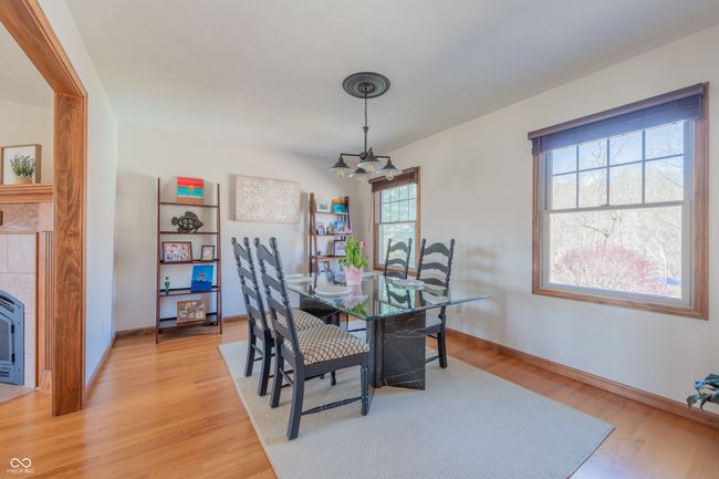 dining room featuring a tiled fireplace, baseboards, a notable chandelier, and light wood-style flooring | Image 9