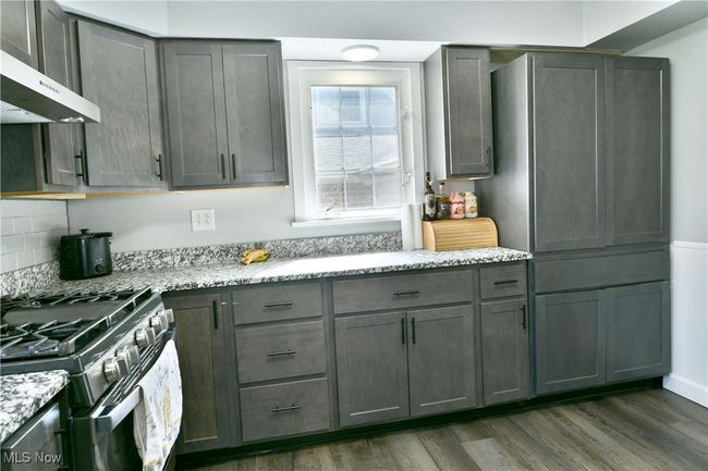 Kitchen with light stone countertops, dark wood-style floors, range with gas cooktop, and range hood | Image 18