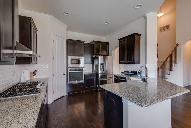 Kitchen featuring arched walkways, appliances with stainless steel finishes, and dark brown cabinets | Image 13