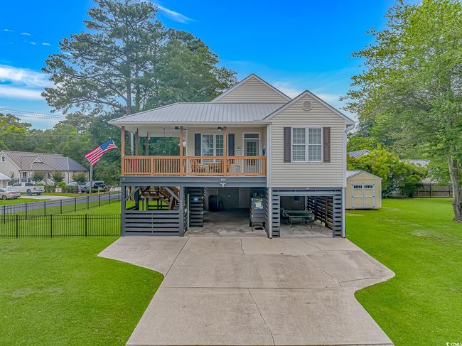 Coastal home featuring a carport, stairs, a ceiling fan, covered porch, and concrete driveway | Image 36
