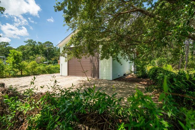 View of yard with dirt driveway, an outdoor structure, and an attached garage | Image 21