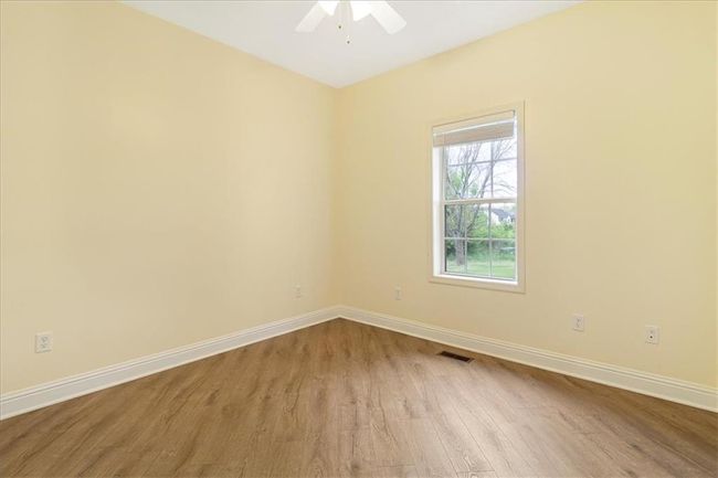 Spare room with baseboards, a ceiling fan, wood finished floors, and visible vents | Image 20
