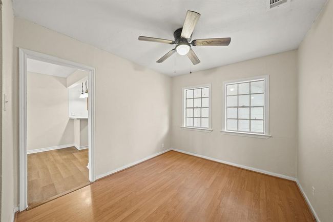 Spacious dining room with vinyl plank floors, a ceiling fan, and windows providing natural light throughout the day. | Image 6