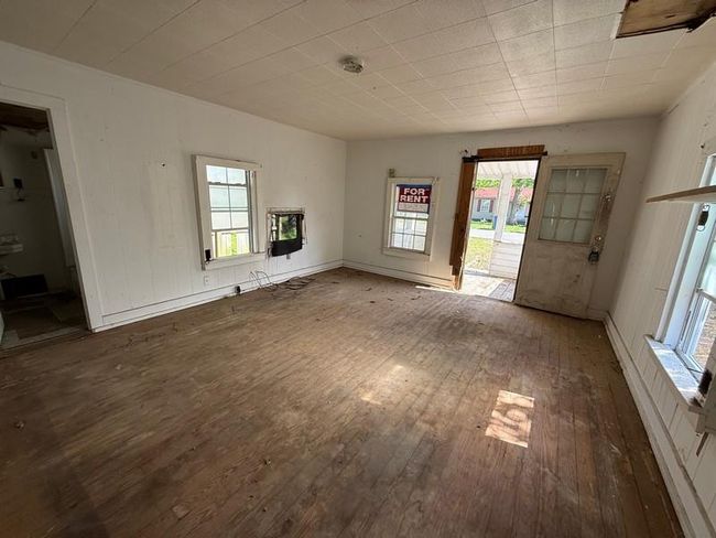 Unfurnished living room featuring hardwood / wood-style floors, healthy amount of natural light, and heating unit | Image 7