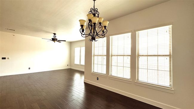 Unfurnished room featuring dark wood finished floors, a chandelier, and a ceiling fan | Image 4