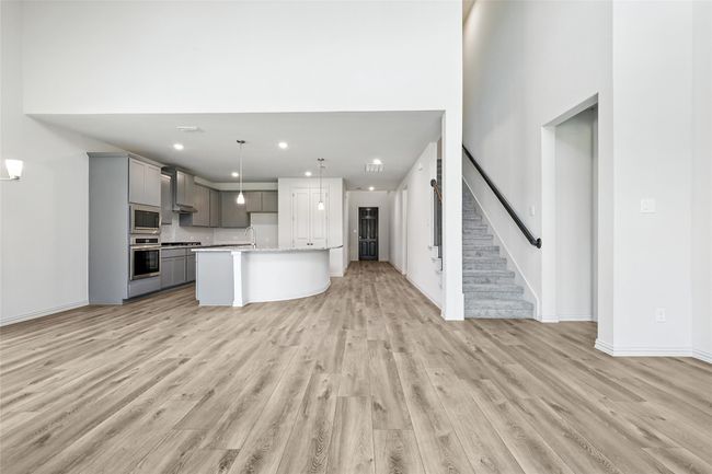 Kitchen with gray cabinets, appliances with stainless steel finishes, open floor plan, wall chimney range hood, and light wood-type flooring | Image 11