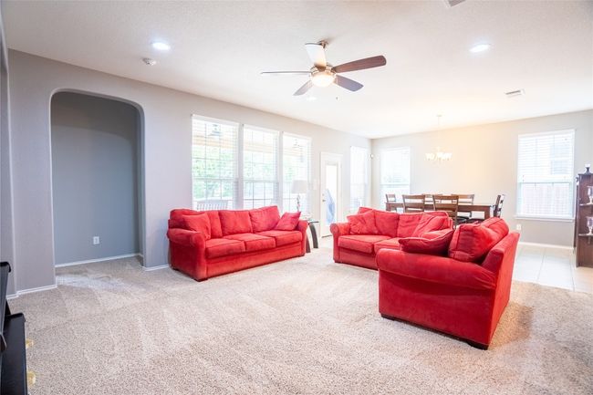 Carpeted living area with ceiling fan, plenty of natural light, recessed lighting, and a chandelier | Image 11