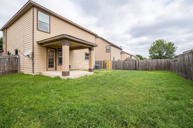 Rear view of property featuring a fenced backyard, central AC unit, a yard, and a patio | Image 35