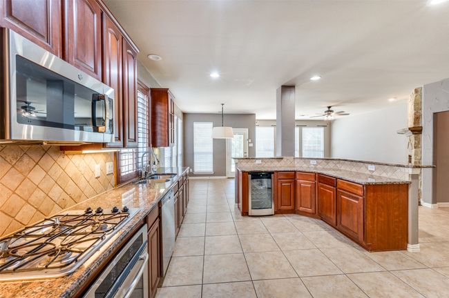 Kitchen featuring stainless steel appliances, beverage cooler, recessed lighting, and tasteful backsplash | Image 9