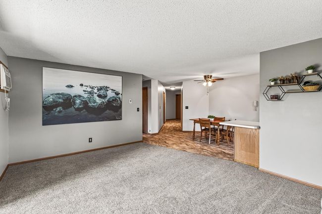 Here is a reverse view from the living room into the dining room. The center hall leads to the main entry, laundry room, and primary suite. In the hall to the left you will find the second bedroom and a full bathroom. | Image 6