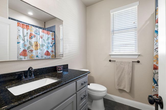 Full bathroom with curtained shower, toilet, tile patterned flooring, and vanity | Image 29