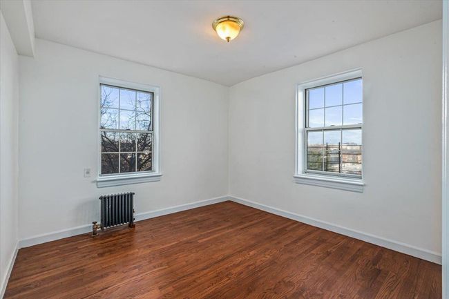 Bedroom featuring hardwood / wood-style floors, a healthy amount of sunlight, and radiator heating unit | Image 11