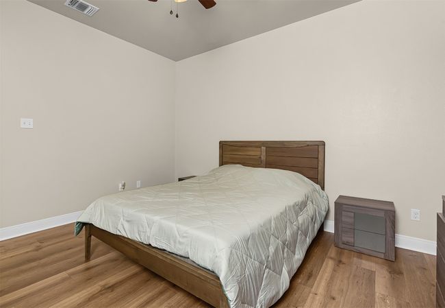 Bedroom featuring ceiling fan, visible vents, baseboards, and wood finished floors | Image 14