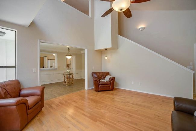 Living room featuring light wood-style flooring, a ceiling fan, and a high ceiling | Image 22