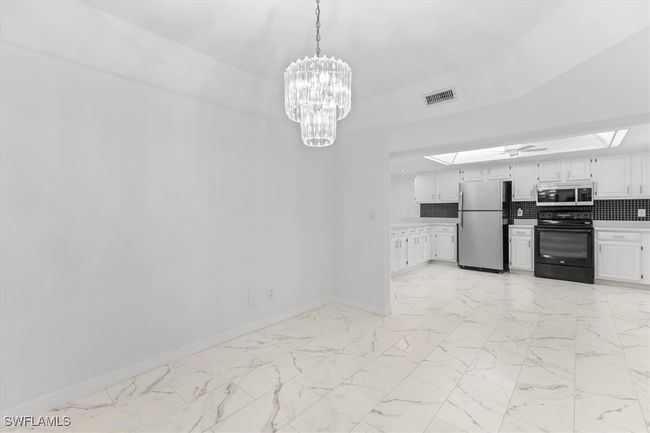 Kitchen with decorative backsplash, white cabinetry, appliances with stainless steel finishes, and light tile patterned floors | Image 30