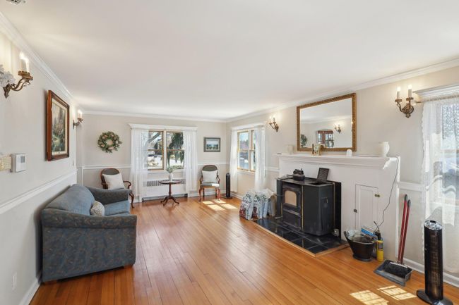 Living room featuring baseboards, ornamental molding, radiator heating unit, a wood stove, and hardwood / wood-style floors | Image 8