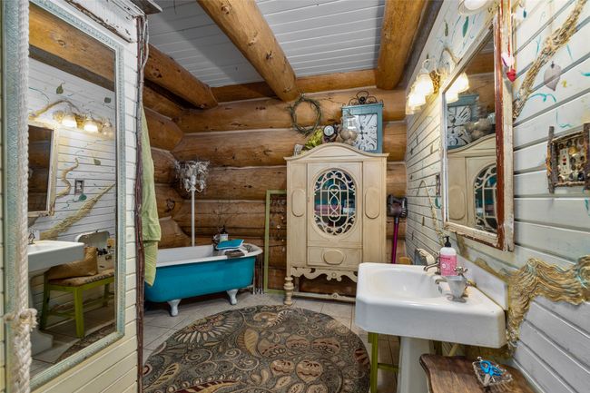 Bathroom with a freestanding tub, rustic walls, beamed ceiling, and tile patterned flooring | Image 17