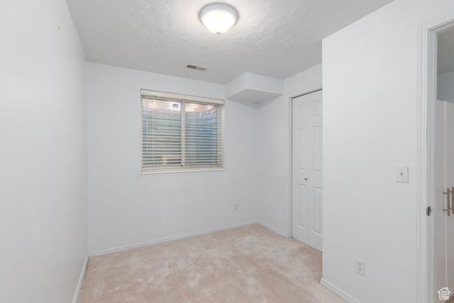 Unfurnished bedroom featuring light carpet, a textured ceiling, baseboards, and a closet | Image 20