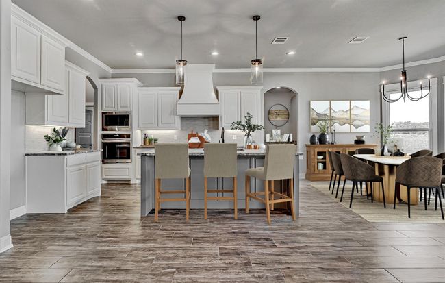 Kitchen featuring appliances with stainless steel finishes, premium range hood, arched walkways, backsplash, and crown molding | Image 12