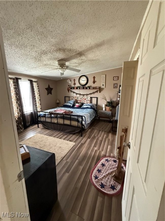 Bedroom with a ceiling fan, dark wood-style flooring, and a textured ceiling | Image 17