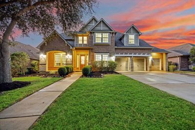 As you approach, you are greeted by lush landscaping that beautifully complements the home's exterior. A paved walkway leads to the covered front entrance, creating a warm and inviting environment that enhances the home’s curb appeal. | Image 2