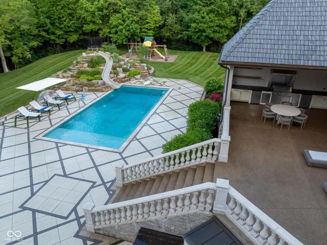 swimming pool featuring a water slide, a patio, and a yard | Image 99