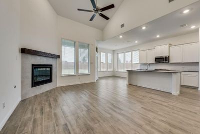 Kitchen with light hardwood / wood-style floors, high vaulted ceiling, a tiled fireplace, and white cabinetry | Image 3