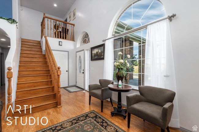 Entrance foyer featuring healthy amount of natural light, stairway, wood finished floors, a towering ceiling, and baseboards | Image 8