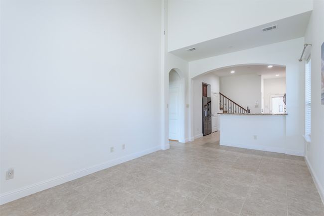 Empty room featuring visible vents, arched walkways, baseboards, and stairs | Image 5