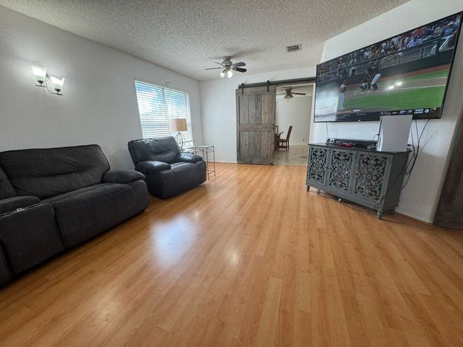 Living area with wood finished floors, a ceiling fan, and a textured ceiling | Image 22