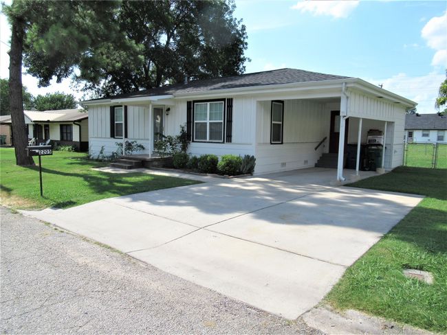 View of front of house featuring fence, concrete driveway, a front yard, board and batten siding, and a carport | Image 4