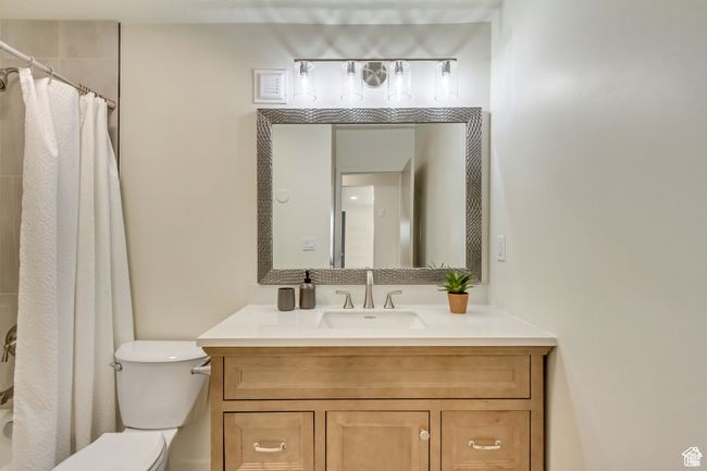 Full bathroom featuring toilet, vanity, and curtained shower | Image 15